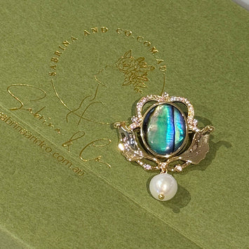 Shell crown with hanging pearl brooch