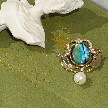 Shell crown with hanging pearl brooch